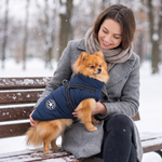 Woman on a snowy bench holding a Pomeranian in the NorthPaw jacket