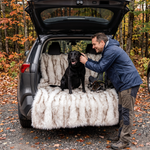 Black Labrador sitting on the SnugShield blanket covering an SUV back seat after a hike
