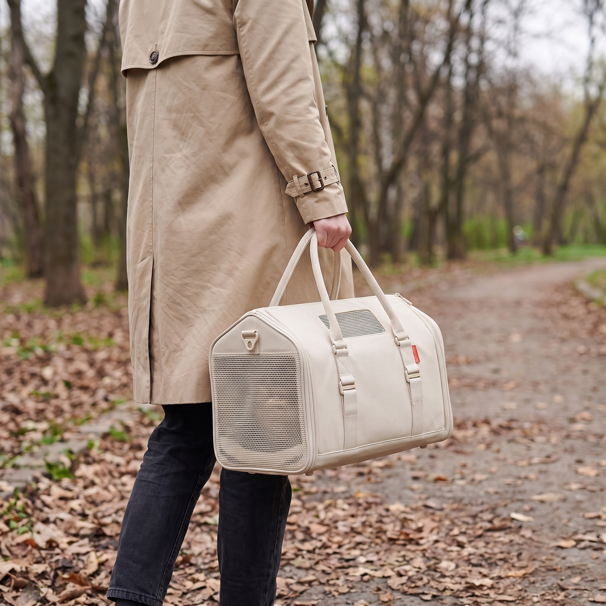Woman carrying her cat in the RoamNest carrier along a park path